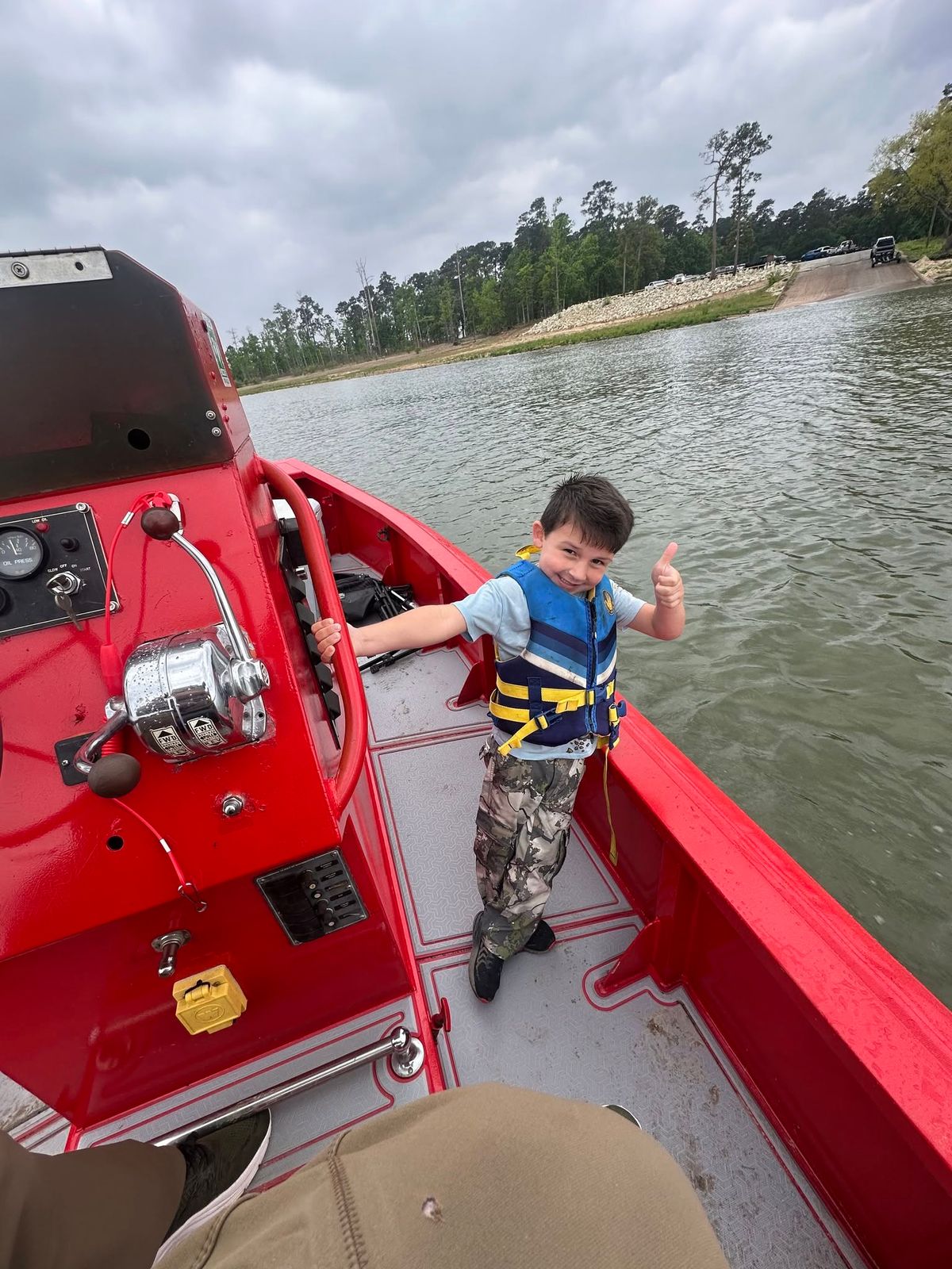 A young passenger in a life jacket standing aboard the red TowBoatUS rescue boat on Lake Fork Reservoir.